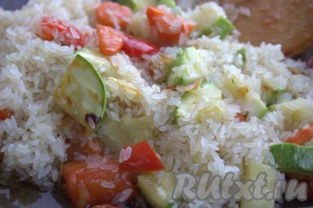 В сковороду к овощам выложить промытый рис, тщательно перемешать.