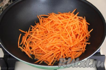 В сковороду с высокими бортиками (я взяла сковороду вок) влить масло, хорошо разогреть его и выложить морковь, натёртую на тёрке для корейской моркови, обжарить, помешивая, в течение 3-4 минут на среднем огне.