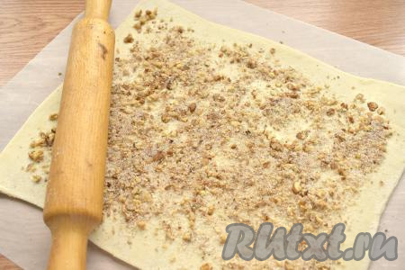 Поверхность раскатанного пласта посыпаем смесью сахара, орехов и корицы, немного вдавливаем начинку в тесто при помощи скалки.