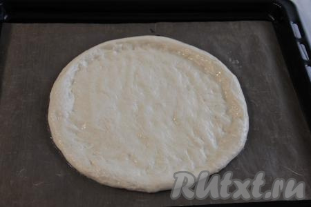 Обмять тесто руками и на противне, застеленном ковриком для выпечки (или пергаментом), сформировать основу для пиццы с толстым краешком.