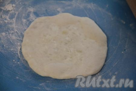 Собрать тесто над начинкой в мешочек, перевернуть на припылённую мукой поверхность и слегка раскатать в круглую лепёшку.