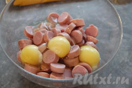 Сосиски нарезать на кружочки толщиной 1 сантиметр, переложить в миску, добавить сырые яйца.