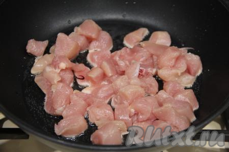 В сковороду влить растительное масло, разогреть его. Куриное филе промыть, немного мясо обсушить, нарезать его на небольшие кубики и выложить в разогретую с маслом сковороду.