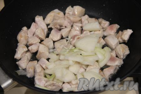 Обжаривать куриное мясо на среднем огне 5 минут, периодически перемешивать. Лук почистить, нарезать на тонкие полукольца и выложить к обжаренному куриному филе, перемешать.