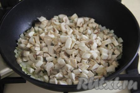 Шампиньоны (или отваренные лесные грибы) нарезать на мелкие кубики и добавить в сковороду к луку.