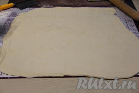 Рабочую поверхность слегка припылить мукой, выложить тесто и раскатать его скалкой в тонкий пласт.