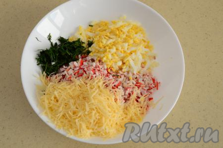 К крабовым палочкам и яйцу выложить мелко нарезанную зелень и натёртый на мелкой тёрке сыр.