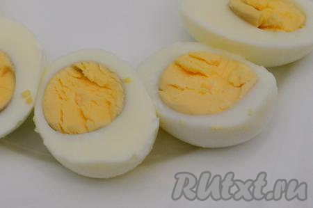 Яйца разрезать вдоль на две части, из каждой половинки достать желток. Желтки переложить в небольшую ёмкость и размять вилкой до однородности. Примерно 1/4 крошки из желтков отложить в сторону (эти желтки нам понадобятся в дальнейшем для украшения).