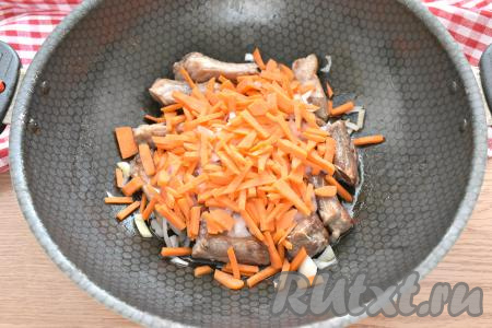 Следом добавляем морковку, нарезанную на небольшие брусочки, перемешиваем, убавляем немного огонь, обжариваем рёбрышки с овощами  5-7 минут, иногда перемешивая.