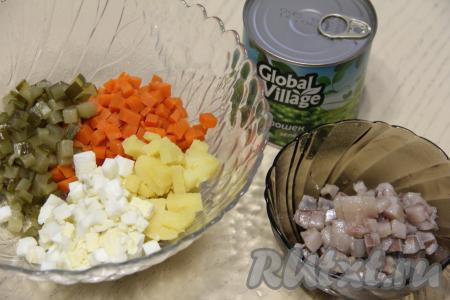 Соединить в миске нарезанные картошку, огурчики, морковь и яйца. Нарезать на небольшие кубики филе сельди.