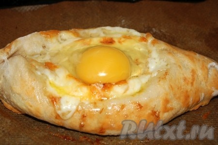 Почти готовые хачапури вытащить и разбить в каждое по сырому яйцу. Снова поставить в духовку и печь примерно 5 минут, пока белок яйца не схватится, желток должен оставаться жидким.