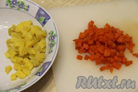 Для того чтобы салат получился более вкусным и красивым, нарезать ингредиенты нужно на небольшие кубики (примерно размером с горошину). Картошку и морковку почистить и нарезать на небольшие кубики, выложить в глубокую миску.