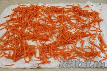 На лаваш, смазанный сыром, равномерно разложить корейскую морковь, немного отступив от краёв лаваша.