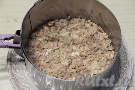 Слить лишний жир с печени трески, а затем размять её вилкой и выложить поверх картофельного слоя, разровнять.