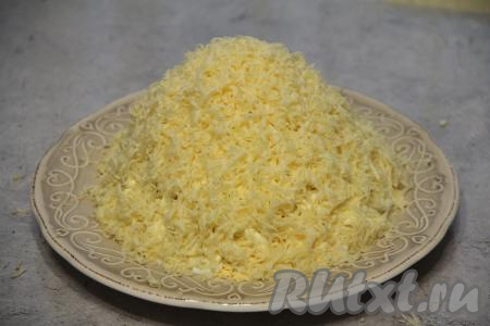 Щедро посыпать салат сыром, натёртым на мелкой тёрке, выравнивая края "пирамиды".