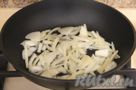 В сковороду влить растительное масло, выложить лук, нарезанный полукольцами, обжарить его, иногда помешивая, на среднем огне в течение 3-4 минут.