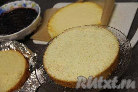 Разрезать остывший бисквит на два коржа. Выложить первый корж на плоскую тарелку (или тортовницу) и пропитать 150 миллилитрами молока. 