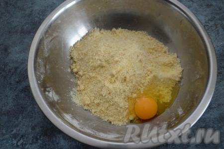 Руками перетереть масло с сухой мучной смесью до образования мелкой песочной крошки. Затем к песочной крошке добавить сырое яйцо.