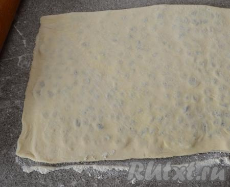 При помощи скалки немного прокатать тесто, чтобы изюм вдавился в тесто. Сильно давить на скалку в процессе раскатывания не нужно, нам нужно лишь соединить 2 части теста, слегка вдавливая изюм.