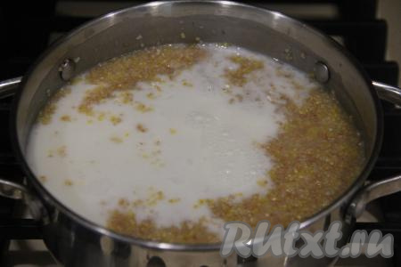Затем влить в кастрюлю молоко, всыпать соль и сахар, перемешать, дать закипеть и варить пшенично-кукурузную кашу на медленном огне 20 минут, время от времени перемешивая. 
