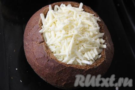 Поверх жульена разложить сыр, натёртый на крупной тёрке. Накрыть жульен хлебной крышкой. Переставить хлеб с жульеном в форму для запекания (или на противень) и отправить в разогретую духовку.