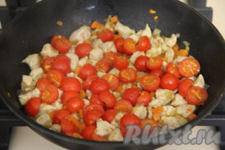 Помидоры черри разрезать пополам и выложить в сковороду. Накрыть крышкой сковороду и томить куриное мясо с овощами 2-3 минуты.