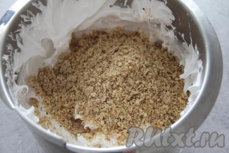 Добавить 250 грамм ореховой крошки во взбитые белки и перемешать лопаткой.
