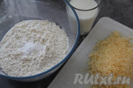 Прежде всего замесим тесто для лепёшек, для этого в миску нужно просеять муку, всыпать соль, соду и сахар, перемешать сухие ингредиенты. 150 грамм сыра натереть на мелкой тёрке.