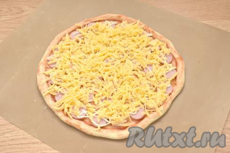 Сыр натираем на крупной тёрке. Половиной натёртого сыра посыпаем пиццу.