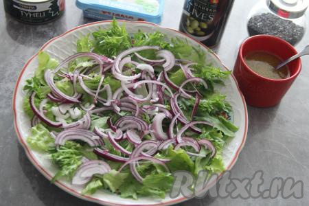 Лук нарезать на тонкие полуколечки и выложить поверх листьев салата.