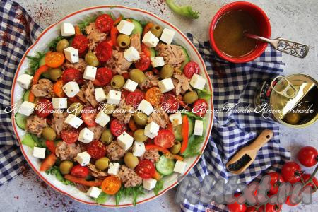 Вкусный, аппетитный греческий салат с тунцом полить сверху заправкой и сразу подать к праздничному или повседневному столу.