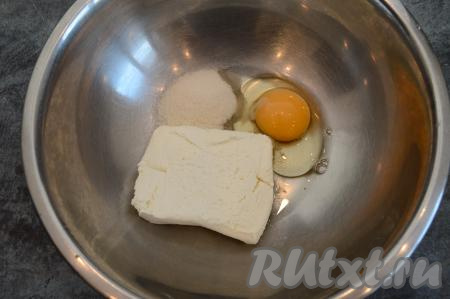 В глубокую миску выложить пачку творога, всыпать сахар и вбить сырое яйцо.