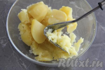 Картошку почистить, переложить в кастрюлю и сварить в подсоленной воде до полной готовности (в течение 20-25 минут). Готовность можно проверить ножом, если он легко входит в корнеплод, значит картофель готов. Слить жидкость, в которой варилась картошка. Переложить картофель в достаточно глубокую миску, остудить и размять толкушкой.