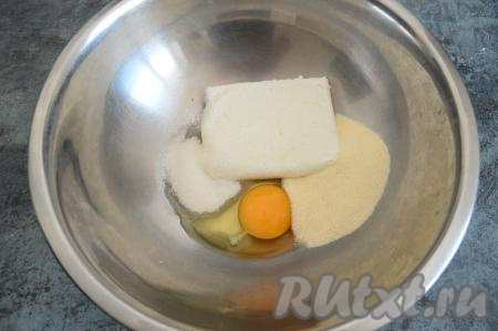 В миску насыпать манную крупу и сахар, выложить творог и сырое яйцо.