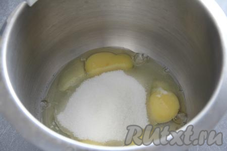 В глубокую миску вбить сырые яйца, всыпать сахар и ванильный сахар.