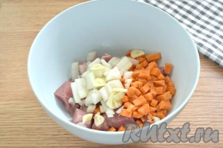 Очищаем морковку, зубчики чеснока и лук. Лук с морковью нарезаем на маленькие кубиками, зубчики чеснока - на достаточно тонкие пластины и перекладываем в миску с кусочками свинины.
