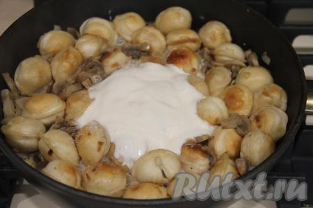 Обжаривать пельмени с грибами и луком 5 минут, не забывая периодически перемешивать. Добавить сметану, соль и специи по вкусу.