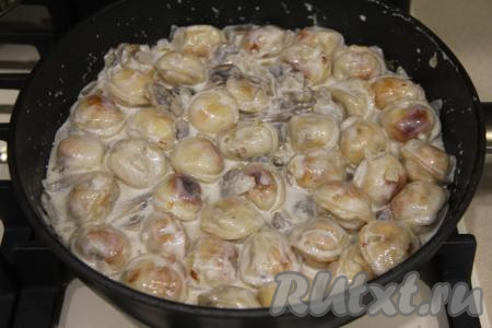 Перемешать пельмени со сметаной и грибами, накрыть сковороду крышкой.