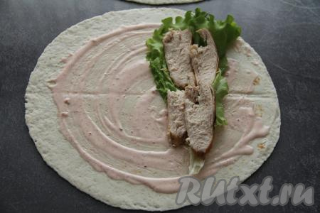 Куриное мясо нарезать на тонкие ломтики. Выложить лист салата ближе к одному краю лепёшки. На лист салата разместить часть нарезанного куриного мяса.