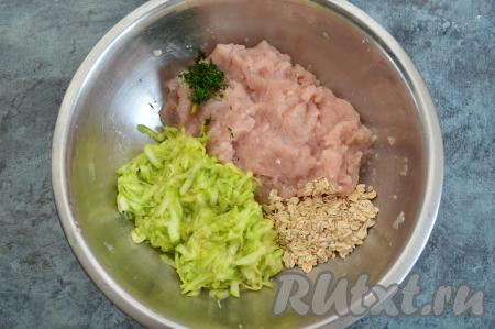 В миску к куриному фаршу выложить отжатый от сока кабачок, нарезанную мелко зелень, овсяные хлопья и соль по вкусу.