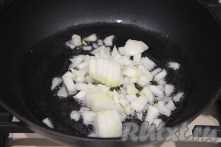 Пока картошка запекается, приготовим начинку. Для этого нужно почистить и мелко нарезать луковицу, затем выложить её в сковороду, разогретую с растительным маслом, и обжарить до мягкости (ориентировочно в течение 5 минут) на среднем огне, иногда помешивая.