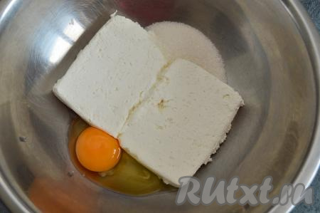 Выложить творог в объёмную миску, добавить сахар и сырое яйцо.