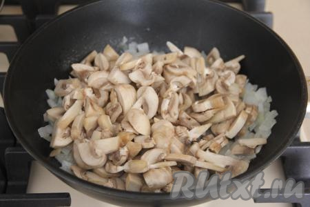 Затем к луку добавить шампиньоны, нарезанные на пластинки. Перемешать грибы с луком и обжаривать минут 10, периодически помешивая.