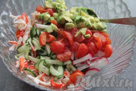 Добавить помидоры и авокадо в салат из крабовых палочек и огурцов, посолить по вкусу.