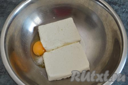В глубокую миску выложить творог, сырое яйцо и щепотку соли.