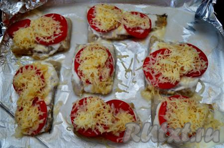 Затем достать форму с рыбой из духовки, присыпать помидоры натёртым на мелкой тёрке сыром.