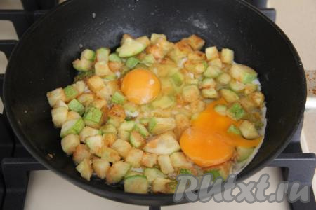 Разровнять обжаренные кабачки так, чтобы они лежали ровным слоем на сковороде, и вбить яйца. Яичные желтки немного присолить.