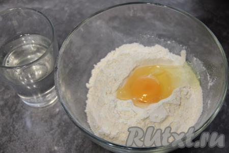 Вбить сырое яйцо и влить холодную воду, перемешивать вначале столовой ложкой, а затем хорошо вымесить тесто руками.