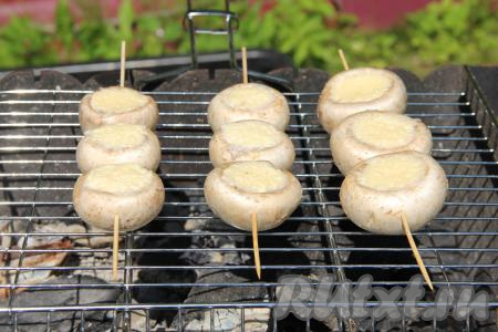 Шпажки с шампиньонами, фаршированными сыром, выложить на подготовленную решётку на мангал. Угли должны быть со средним жаром, без огня. 