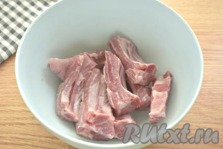 Свиные рёбра ополаскиваем водой и нарезаем по мягкой части мяса на порционные кусочки.